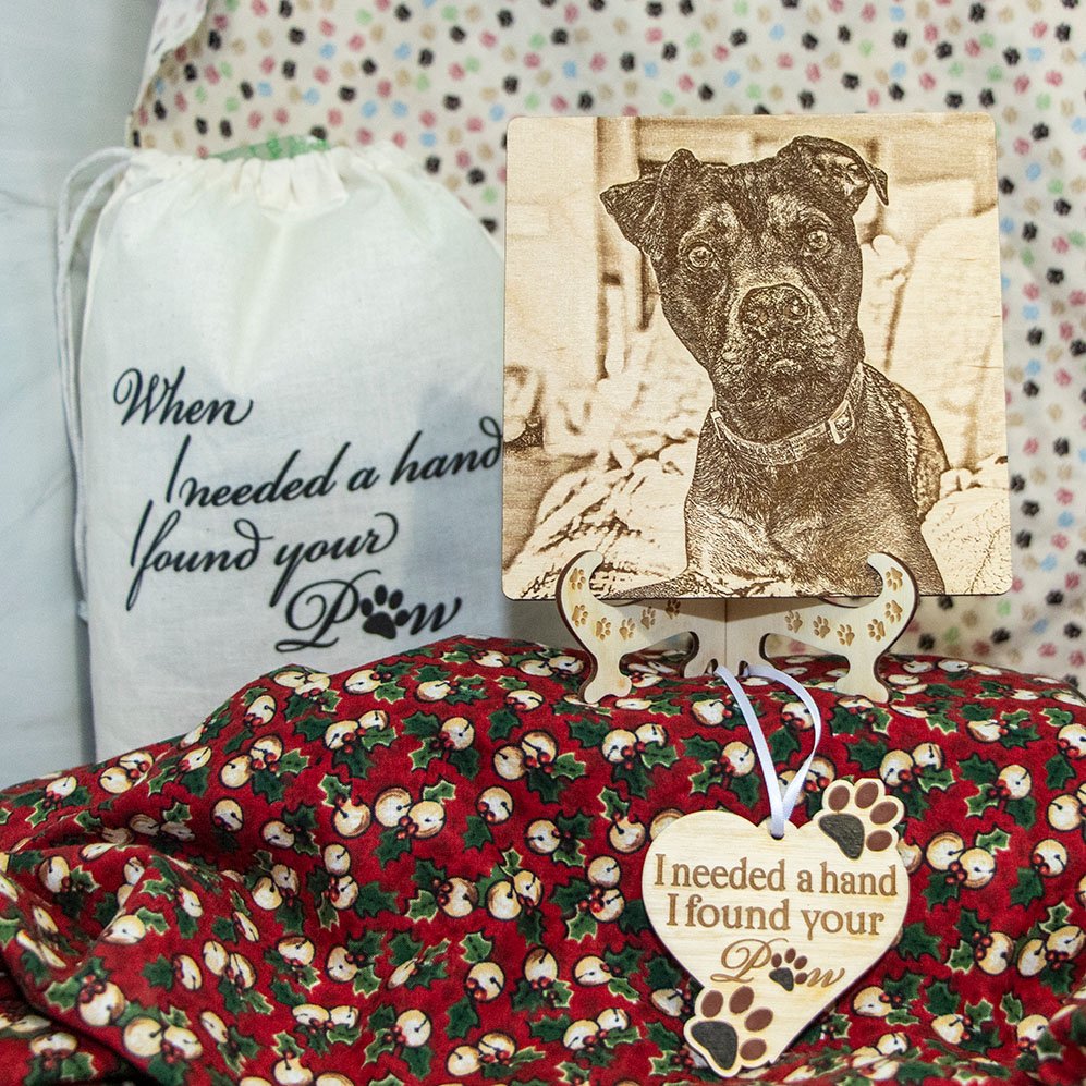 A dog's portrait engraved on wood with a heart ornament reading “I needed a hand, I found your paw”